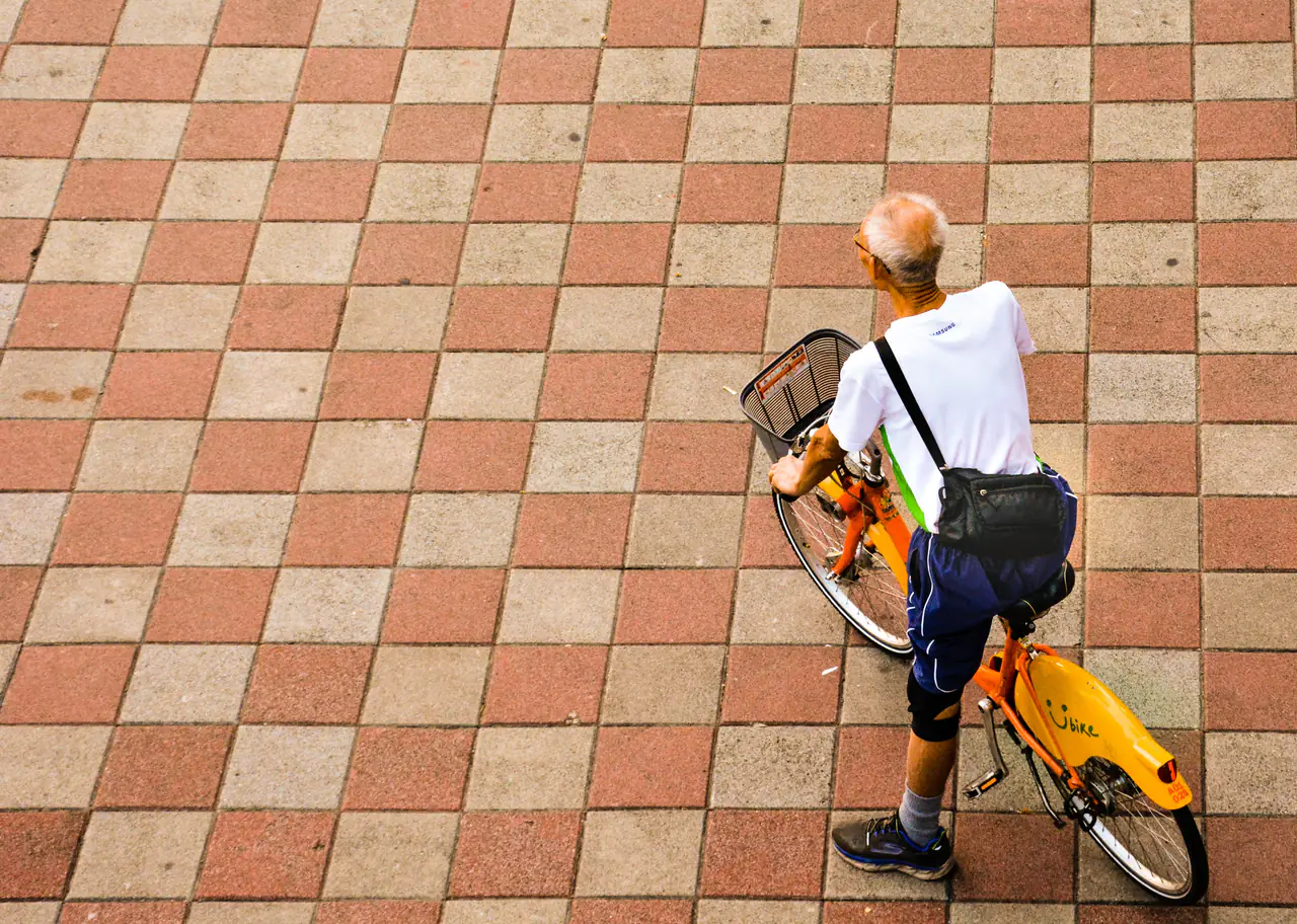 An older man on a hire bicycle, seen from above.