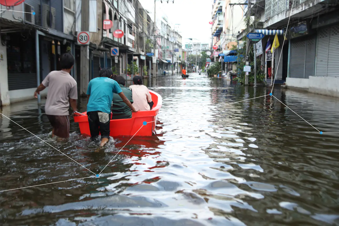 People wading through a flooded city street, pushing a boat.