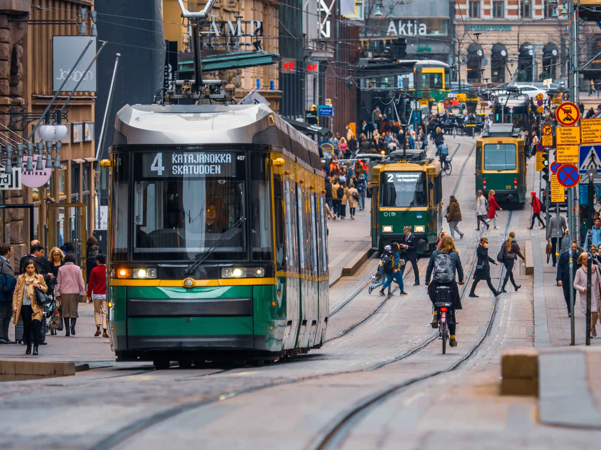 Trams and people on a busy Helsinki street.