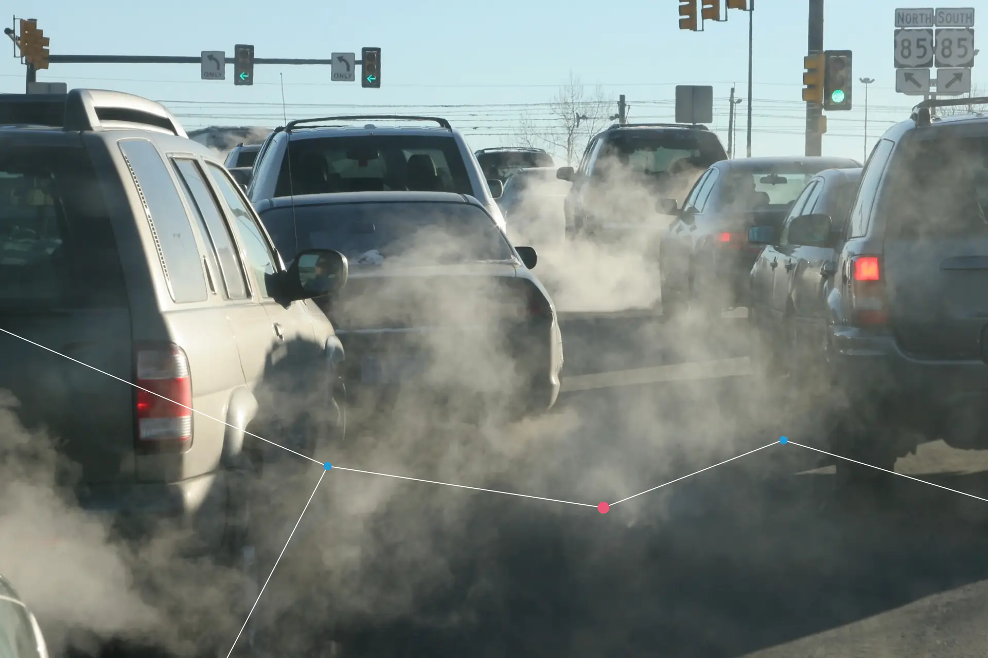 Exhaust fumes rising from traffic queued at a junction.